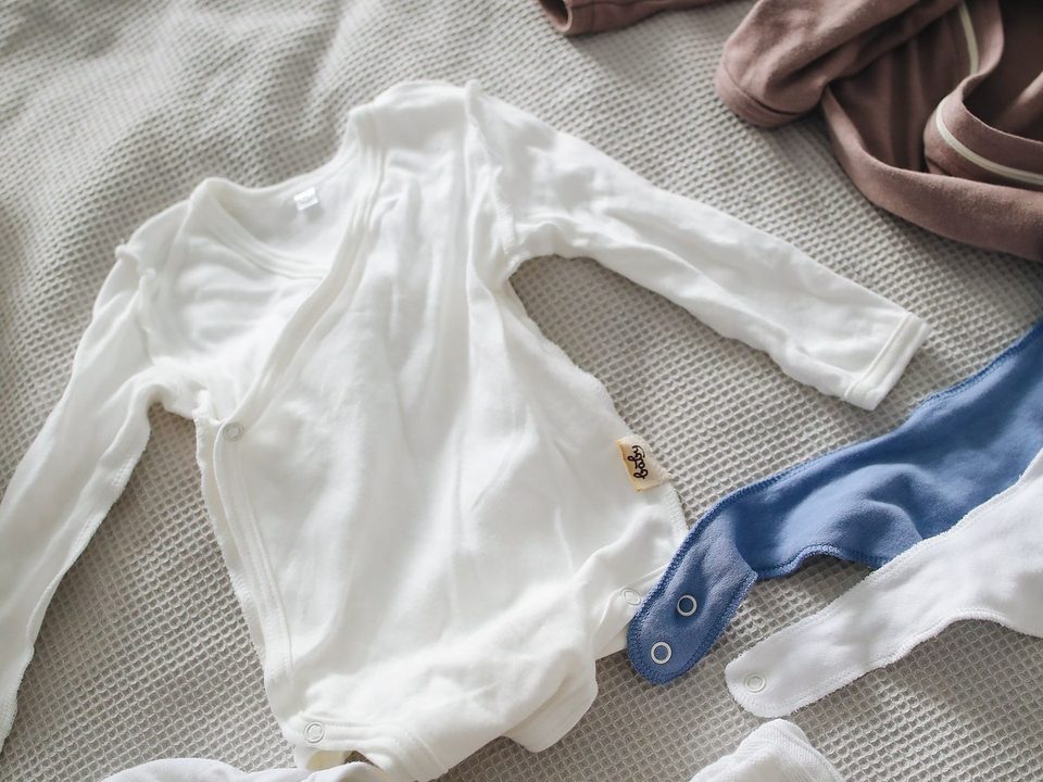 White and blue baby clothing arranged on a textured surface