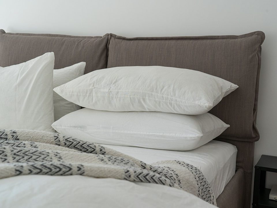 Neutral bedroom with white bed sheets and stacked pillows