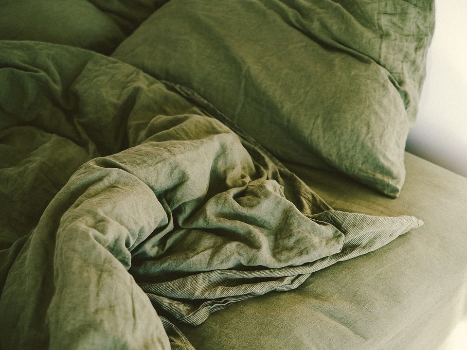 Green linen duvet cover and pillows arranged on a bed