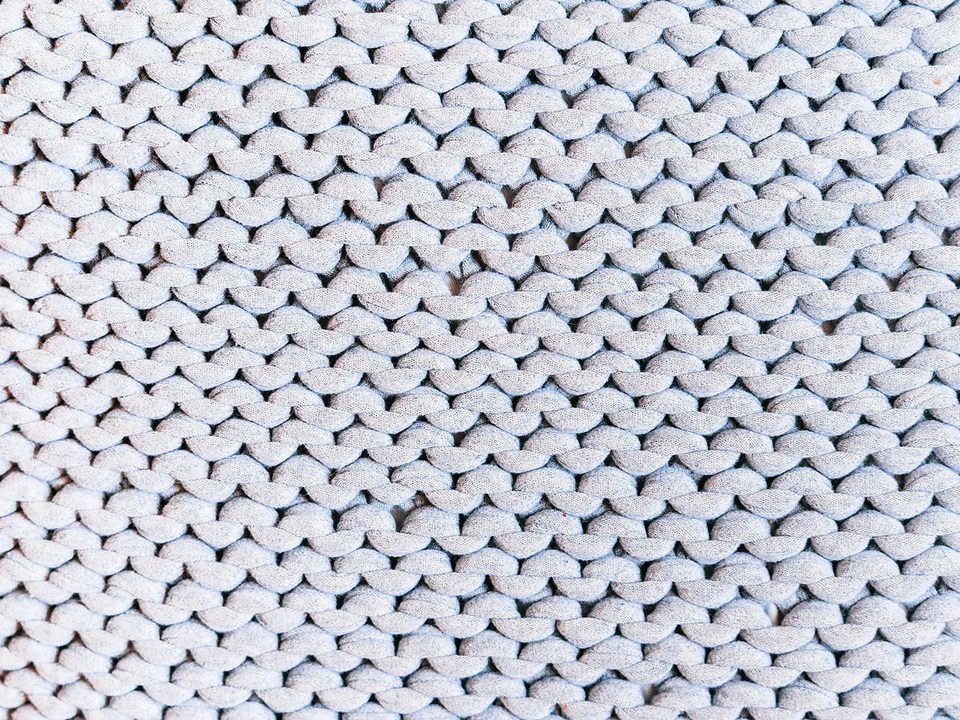 Close-up of white knitted fabric with visible jersey stitches